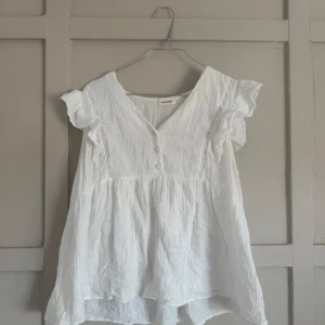 Vit blus från Sweewë - Säljer en söt vit blus från Sweewë med korta ärmar och knappar framtill. Blusen har en luftig passform och fina spetsdetaljer vid ärmarna. Perfekt för varma dagar! Blusen passar som S/M💓💓