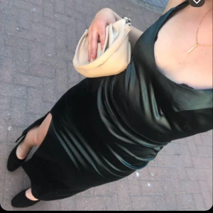 Balklänning  - mörkgrön långklänning i satin med en slits på sidan. Klänningen har en v-ringad design och smala axelband. Den är bara använd en gång och har inga defekter. Skulle säga att det är en storlek S, jag är 172 för referens. Köpt på bubbleroom. Det är även spets i ryggen. Skriv för fler bilder 