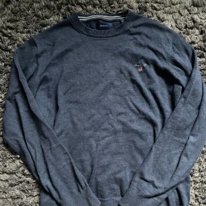 Mörkblå tröja från GANT - Säljer en stilren mörkblå tröja från GANT med broderad logotyp på bröstet. Tröjan har långa ärmar och ribbstickad krage samt ärmslut. I nyskick, inga som helst tecken på skador eller fel. Pris kan diskuteras.