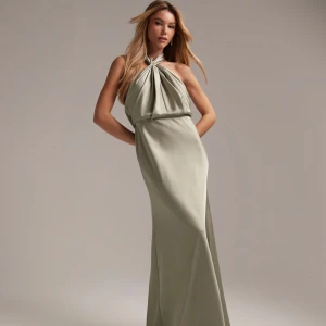 Grön axelbandslös långklänning - Elegant grön långklänning med halterneck-design. Klänningen har en vacker drapering framtill och är perfekt för formella tillfällen. Den är tillverkad i ett mjukt och följsamt material som ger en lyxig känsla. Aldrig använd med prislapp kvar