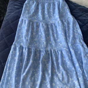 Blå långkjol från Gina Tricot, strl 146/152 - Säljer en blommig kångkjol från Gina Tricot i strl  146/152. Kjolen har resår i midjan.