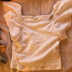 Vit blus från Kappahl - Säljer en söt vit blus från Kappahl med broderade detaljer. Blusen har korta ärmar med volang och en fyrkantig halsringning. Perfekt för sommaren och våren ❣️den säljs inte längre på Kappahl 