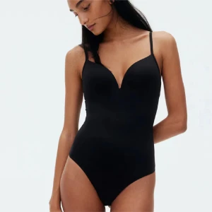 Svart ärmlös bodysuit - Snygg svart bodysuit med smala axelband och djup v-ringning. Perfekt för en stilren look. Oanvänd