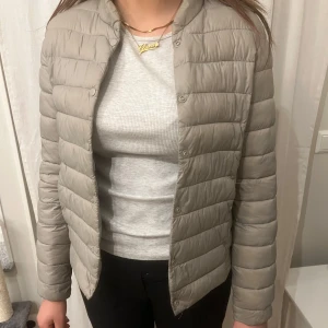 Beige pufferjacka - Säljer en stilren grå pufferjacka med knappar. Jackan har en normal passform och är perfekt för kyligare dagar. Den är lätt och smidig att bära, inte använt den så många ggr och därför säljer jag den💕