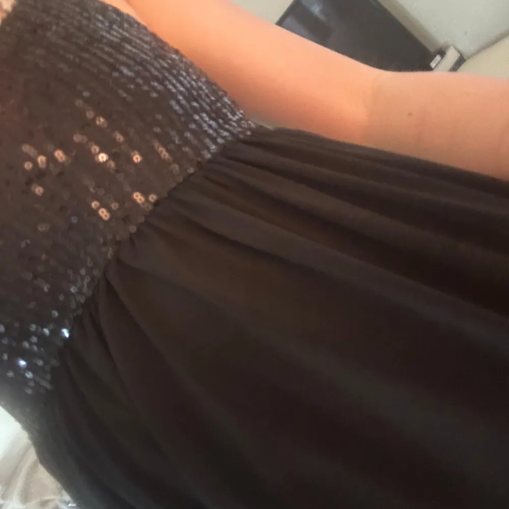 Snygg svart topp från Gina Tricot med glittriga paljetter på överdelen. Toppen har en elegant design med en åtsittande topp och en flödande kjol. Perfekt för en festlig kväll!. Puserot.