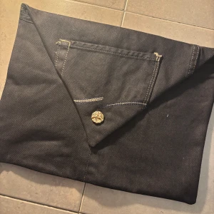 Datafodral i svart jeanstyg - Unikt datafodral i svart jeanstyg med guldknapp. Insidan är fodrad med ett mjukt silkestyg för extra skydd. Passar 13 tum (vanlig skoldator)