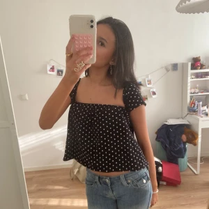 Svart prickig topp - Säljer en söt svart offshoulder topp med vita prickar. Toppen är croppad och har en luftig passform, perfekt för varma dagar. Den är stilren och lätt att matcha med olika outfits. Passar mig som har storlek S