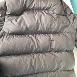 Mörk blå pufferjacka med dragkedja - Säljer en svart pufferjacka från Ralph Lauren med dragkedja och en liten röd logga på bröstet. Jackan har långa ärmar och flera praktiska fickor med dragkedja. Perfekt för kyliga dagar!