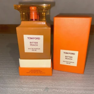 Tom Ford Bitter Peach Eau de Parfum 100 ml - Säljer en lyxig Tom Ford Bitter Peach Eau de Parfum i en elegant orange flaska med matchande förpackning. Flaskan rymmer 100 ml och har en stilren design med en fyrkantig form och en gyllene kork. Perfekt för den som älskar fruktiga och intensiva dofter.pris går att diskutera 