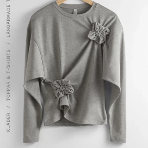 Grå långärmad topp med blommiga detaljer - Snygg grå långärmad topp med unika blommiga detaljer framtill från Other stories. Nästan aldrig använd!
