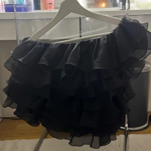 Svart volangtop - Snygg svart offshoulder-top med flera lager av volanger. Perfekt för en kväll ute eller en speciell tillställning. Toppen har en luftig och elegant design som ger en chic look. Skit snygg verkligen, men hittar inte tillfällen för att använda den. Storlek 36 men passar mig som brukar ha 32/34 i toppar! Den är endast använd en gång. Så den är som ny! Nypris 400kr. Mitt pris 250kr 