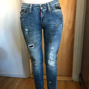 Dsquared2 jeans  - Snygga blå jeans från Dsquared2 slitna detaljer och dragkedjor. De har en hög midja och en straight passform. Perfekta för en avslappnad stil med en cool edge.