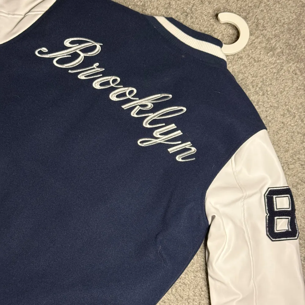 BASEBALLJACKA “BUD” – Lager157, strl XS Snygg mörkblå baseballjacka från Lager157 i modell “BUD”. Stilren design med “New York Brooklyn” text. Storlek XS, i nyskick (10/10), knappt använd. Perfekt för en sportig och trendig look! Pris kan diskuteras vid snabb affär.. Takit.