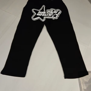Svarta mjukisbyxor från FSBN - Snygga svarta mjukisbyxor från FSBN med ett coolt vitt tryck på baksidan. Byxorna har en avslappnad passform och är perfekta för en bekväm stil. Tillverkade i Turkiet.