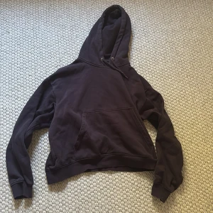 Brun hoodie med ficka framtill Weekday - Säljer en klassisk brun hoodie med en stor ficka framtill och justerbar huva. Perfekt för en avslappnad stil. Den har långa ärmar och ribbade muddar vid ärmslut och nederkant.