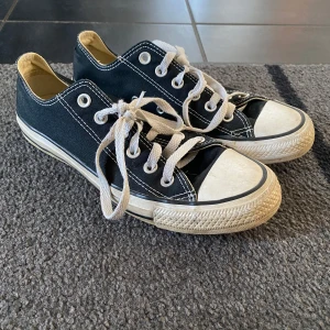 Svarta Converse All Star sneakers - Klassiska svarta Converse All Star sneakers med vit sula och snörning. Perfekta för en avslappnad stil. De har den ikoniska loggan på hälen och en slitstark gummisula. Äkta!! Nypris 800 