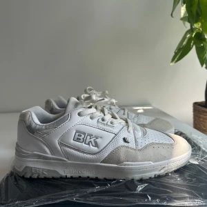 Vita sneakers från British Knights 44  - Snygga vita sneakers från British Knights med BK-logga på sidan. Skorna har en chunky sula, snörning och detaljer i både skinn och mocka. Perforerade partier framtill för extra andningsförmåga och en klassisk, sportig look. Storlek 44