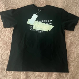 Maison Margiela t-shirt med tryck - Säljer två t-shirts från Maison Margiela, en svart och en vit. Båda har det ikoniska numrerade trycket framtill, där siffran 6 är markerad. Klassisk passform och rund hals. Perfekt för dig som gillar stilrena och trendiga plagg. Paketpris 1100, 600kr styck. Lappen säger s men sitter som M