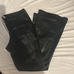 Svarta skinnbyxor från Bershka - Snygga svarta skinnbyxor från Bershka med kostymbyxform. Lågmidjade och bootcut. Rikysnygga och använda fåtal gånger säljer pga har för många skinnbyxor 