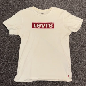 Vit Levi's t-shirt med röd logga - Vit t-shirt från Levi's i bomull med klassisk röd logga tryckt på bröstet. Modellen är kortärmad och har en normal passform. 
