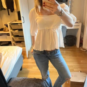 Vit blus med volang och knyt - Säljer en söt vit blus med volang och knyt under bysten. Blusen har trekvartsärm och en lätt v-ringning. 