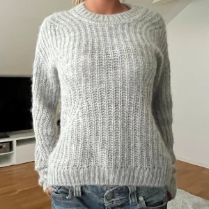 Ljusgrå stickad tröja från Esprit - Säljer en ljusgrå stickad tröja från Esprit. Tröjan har ett grovt ribbat mönster, rund halsringning och långa ärmar. Perfekt för kyligare dagar och enkel att matcha med jeans eller kjol.