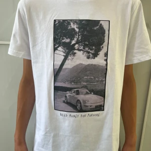  Porsche 911 - T-shirt - Vit t-shirt med Porsche 911 tryck från Capsters. Tröjan är helt ny och har aldrig andvänds. Det finns flera storlekar och killen på bilden är ungefär 175 cm och bär storlek S. Priset kan diskuteras och tveka inte att kontakta vid frågor. 