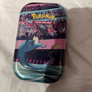 Pokémon Trading Card Game Tin - Cool Pokémon-tin med färgstark design och motiv från Pokémon Trading Card Game. Perfekt för att förvara och samla dina favoritkort! Passar både nya och erfarna samlare som vill ha en snygg och praktisk förvaringslåda.