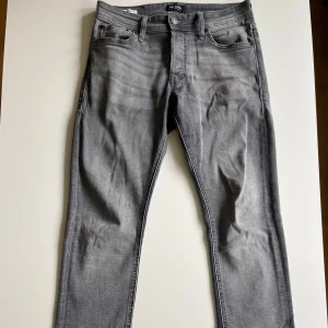 Grå slim fit jeans från Jack & Jones - Snygga grå jeans från Jack & Jones i slim fit-modell. Jeansen är snygga med det lätt tvättad looken framtill. Säljer för 150kr