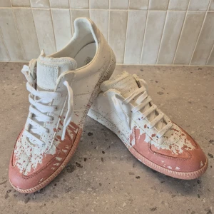Maison Margiela sneakers - Maison Margiela sneakers i vitt med  färgstänk. Använda 1 gång. Köpte fel storlek. 