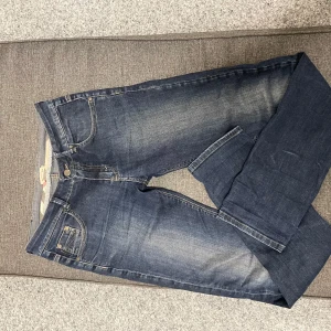 Mörkblå jeans från Burberry, stl 14Y - Snygga mörkblå jeans från Burberry med klassisk femficksdesign och diskret slitning framtill. Jeansen har raka ben och är tillverkade i mjukt denimtyg med detaljer i kontrastsömmar. Perfekta för dig som gillar stilrena och tidlösa jeans.
