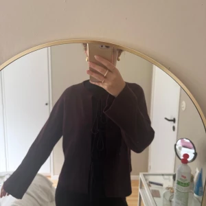 Vinröd kofta med knyt fram - Säljer en vinröd kofta med knyt framtill. Koftan har lång ärm och är i ett mjukt, stickat material. Perfekt att slänga över en topp för en snygg lager-på-lager-look.