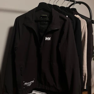 Helly Hansen Vindjacka! - Tjena! 👋 Säljer denna stilfyllda helly hansen vindjackan, perfekt  nu inför sommaren | Säljer då den ej kommit till användning 🙏 | Pris: 699kr 💵| Skick: 10/10 🙌 | Garanterar att skicka paletet inom 24H vid möjlighet 📦 📬 | Kom PV för andra frågor ! ✅