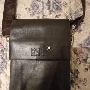 Svart axelväska från Montblanc - Snygg svart axelväska från Montblanc med justerbar rem och flera fack. Väskan har dragkedja, präglad logotyp på framsidan och är tillverkad i skinn. Perfekt för att bära med sig det viktigaste.