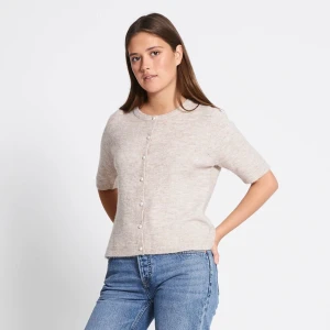 Beige kofta med kort ärm och pärlknappar - Säljer en beige kofta med korta ärmar och rund hals. Koftan har fina pärlknappar framtill och är stickad i ett mjukt material. Perfekt att styla med jeans eller kjol för en enkel och stilren look.