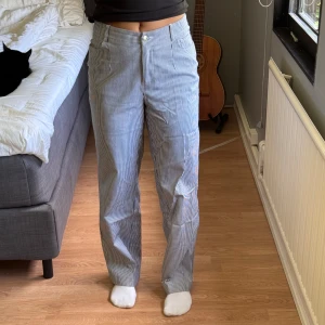 Blåvit randiga byxor med hög midja - Snygga blåvit randiga byxor i stretchigt material med hög midja och raka ben från NA-KD. Klassisk passform med dragkedja och knapp framtill. Använda endast ett fåtal gånger. 100kr