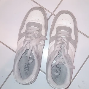Vita och grå sneakers - Säljer ett par vita och grå sneakers från 157 med klassisk design. Skorna har snörning och platt sula, samt rund tå. Perfekta för dig som gillar en enkel och stilren look till vardags.