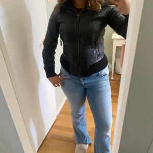 Svart skinnjacka från Bruno Zaragoza - Säljer en svart skinnjacka från Bruno Zaragoza med dragkedja framtill och två snedställda fickor med dragkedja. Jackan har ribbade muddar vid ärmslut, krage och nederkant. Perfekt för dig som gillar en klassisk och stilren look.