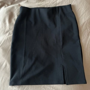 Svart minikjol - En svart kort kjol med en diskret slits framtill. Resår i midja och stretchigt material 