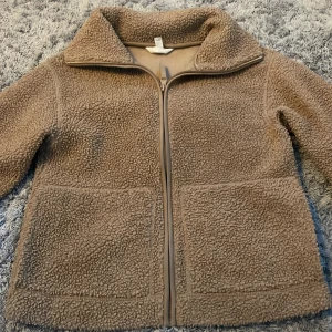 Beige teddyjacka med dragkedja - Mysig trendig beige teddyjacka med hel dragkedja framtill och två stora fickor. Jackan har hög krage och lång ärm, perfekt för sommarkvällar. Använt 1 gång!