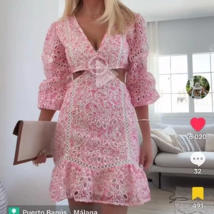 Rosa blommig kortklänning med volang och spets - Superfin rosa kortklänning med blommigt spetsmönster, volangkant och markerad midja. Klänningen har v-ringning, trekvartsärmar och en snygg cut-out detalj framtill. Perfekt för sommarens alla tillfällen! Aldrig använd med prislapp kvar, storlek L men skulle säga att den passar M. Nypris 3500kr