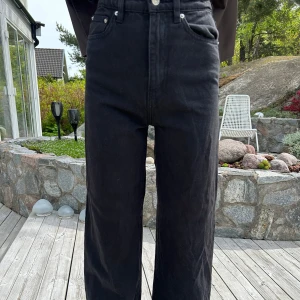 Svarta vida jeans - Säljer ett par svarta jeans med hög midja och raka, vida ben. Klassisk femficksmodell med knapp och dragkedja framtill. Perfekta för en avslappnad och trendig look.🌺