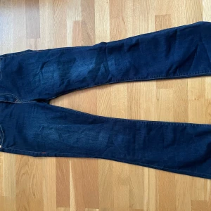 Mörkblå True Religion jeans BECCA - Säljer ett par mörkblå True Religion BECCA jeans med bootcut. Jeansen har snygga kontrastsömmar, två fickor med lock och knappar bak samt klassisk True Religion-lapp. Mid rise och tillverkade i jeansmaterial.