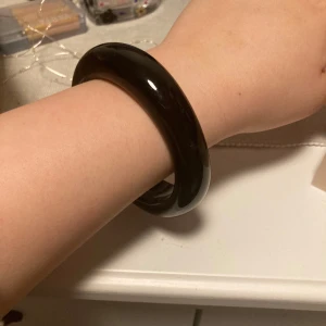 Svart chunky armband - Säljer ett svart chunky armband med rund och tjock design. Armbandet är slätt och har en glansig finish, perfekt för att ge en cool touch till din outfit.