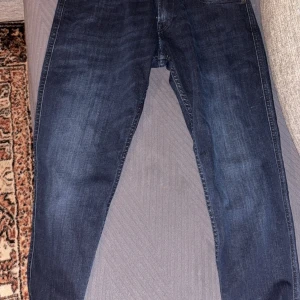 Mörkblå jeans från replay slim fit 30/30 - Mörkblå jeansbyxor i klassisk modell med raka ben och fem fickor. Jeansen har en enkel design utan synliga slitningar eller dekorationer. Perfekta för en stilren och avslappnad look. Helt nya aldrig andvända
