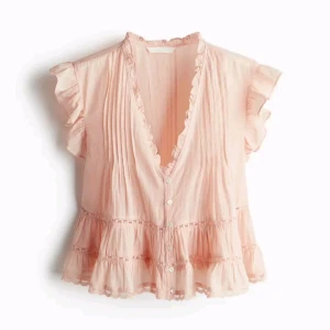 Ljusrosa volangblus - Supersöt ljusrosa blus med volangdetaljer och knappar framtill. Blusen har v-ringning, korta volangärmar och är tillverkad i ett lätt, luftigt material. Perfekt för en romantisk och feminin stil.