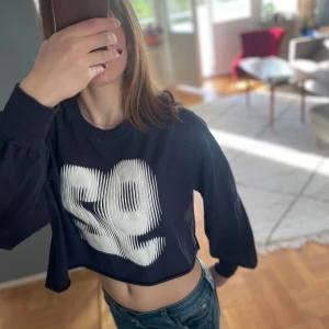 Mörkblå croppad sweatshirt med tryck från Monki - Säljer en mörkblå croppad sweatshirt från Monki i storlek M. Tröjan har ett stort vitt tryck med siffran 92 på framsidan och långa ärmar med muddar. Lite missfärgning på det vita om man tittar noga, inget som stör. 