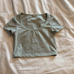 Ljusgrön croppad t-shirt från H&M - Säljer en ljusgrön croppad t-shirt från H&M. T-shirten har rund halsringning och korta ärmar. Träningströja i skönt bomullsmaterial