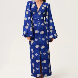 Blå långklänning med blommigt mönster - Säljer den här underbara klänning som jag använt endast en gång då jag tycker den är lite liten på mig, de är den populära modellen från adoore och den är i storlek 36 de ända som är fel på den är att knappen längst ner har lossnat men har gjort så att de ser ut som att klänningen ska vara så alltså inget man märker eller tänker på