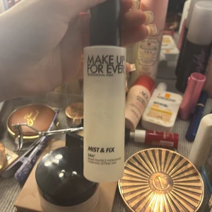 Make Up For Ever Mist & Fix - Make Up For Ever Mist & Fix är en genomskinlig face mist i en frostad plastflaska med svart lock. Den återfuktar och fixerar sminket för en långvarig look. Perfekt att spraya över makeupen för extra hållbarhet och fräsch finish. Förpackning finns